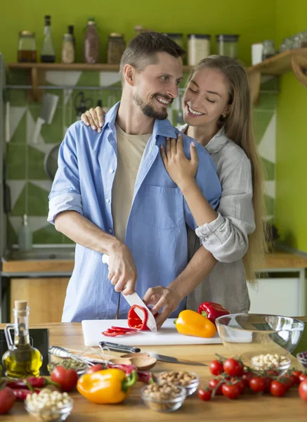 Omfamnande par som gör läcker färsk grönsakssallad — Stockfoto