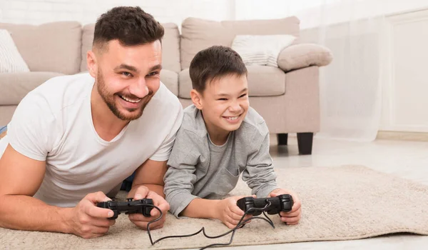 Allegro padre e figlio che giocano ai videogiochi a casa — Foto Stock