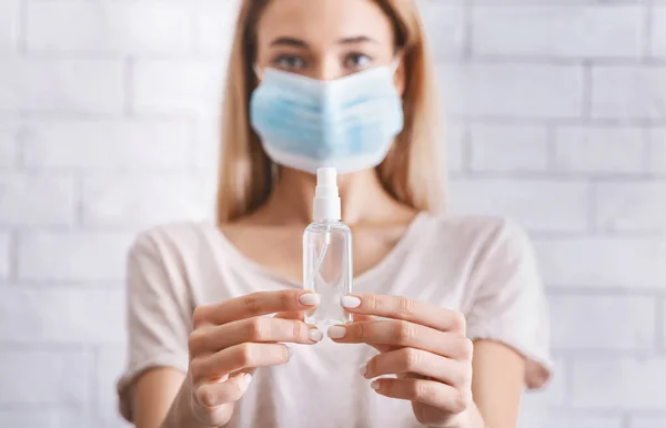 Женщины в медицинской маске и антисептик в руках — стоковое фото