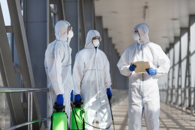 Virüs korumalı giysiler içindeki adamlar şehri dezenfekte etmeyi planlıyor.