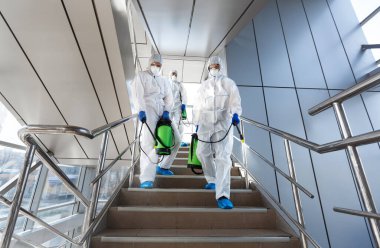 Government workers in protective suits making disinfection of stairs clipart