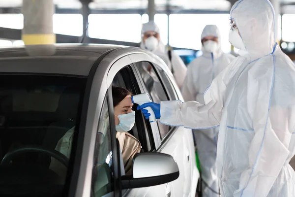 Trabalhador médico medir a temperatura da mulher através da janela do carro — Fotografia de Stock