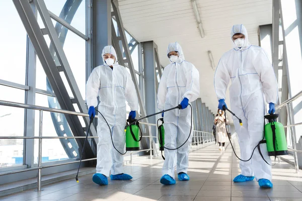 El personal médico que usa ropa protectora desinfecta el lugar público — Foto de Stock
