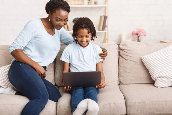 Afro mãe e filha usando laptop no sofá — Fotografia de Stock