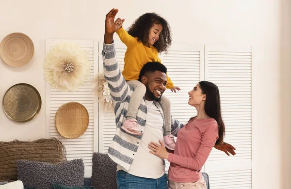 Familia internacional divertirse. Padre sostiene a la hija en hombros — Foto de Stock