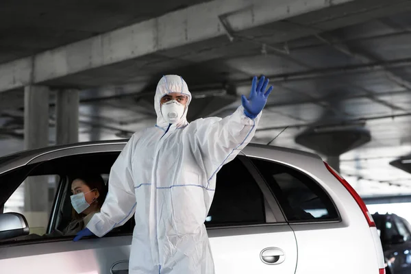 Homem de terno protetor mostrando sinal de parada, mulher no carro está doente com coronavírus — Fotografia de Stock