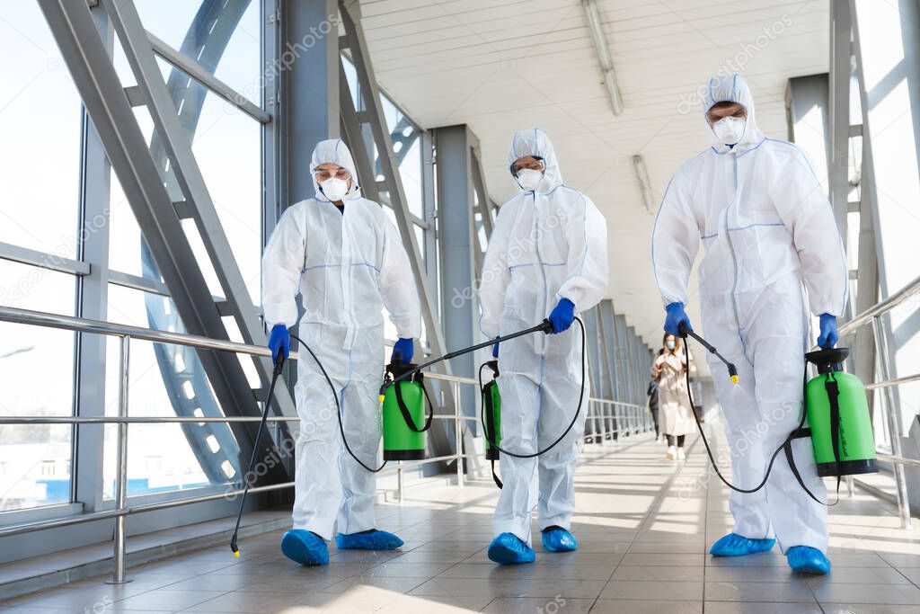 Medical staff wearing protective clothing disinfects the public place