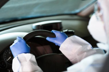 Coronavirus hazmat, eldiven ve yüz maskesi takan kişi araba kullanıyor.