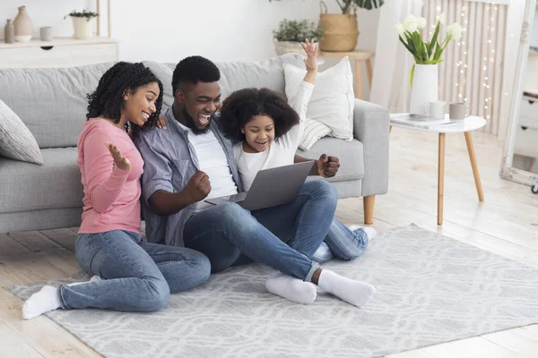 Mãe, pai e filha africanos comemorando o sucesso com laptop em casa — Fotografia de Stock