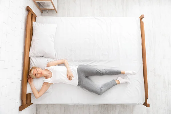 Horní pohled na ženu ležící v posteli se zavřenýma očima — Stock fotografie