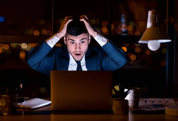 Geschockter Geschäftsmann mit Schröpfkopf schaut auf Laptop im Büro — Stockfoto