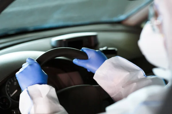 Seseorang di coronavirus hazmat, sarung tangan dan masker wajah mengendarai mobil — Stok Foto