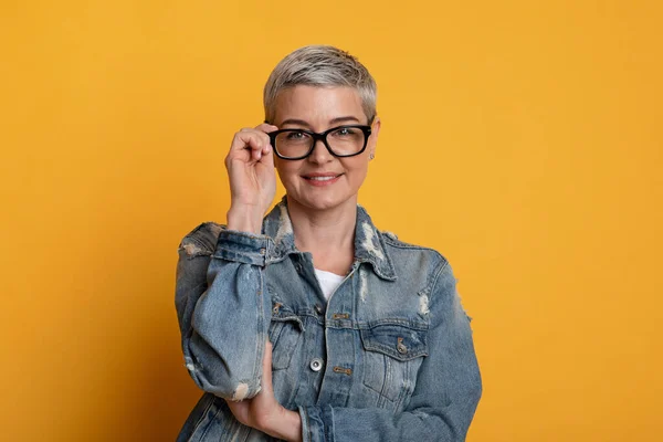 Retrato de mujer de mediana edad confiada en gafas sobre fondo amarillo —  Fotos de Stock