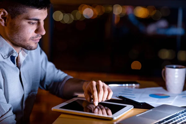 Empreendedor sério usando tablet sentado no escritório trabalhando à noite — Fotografia de Stock