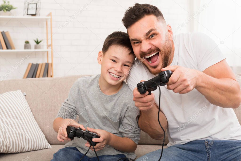 Dad and son with joysticks playing video games at home