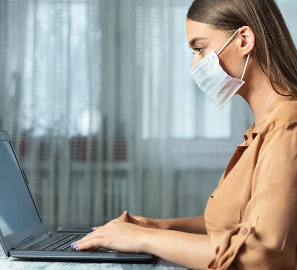 Женщина в маске и работает с ноутбуком, крупным планом — стоковое фото