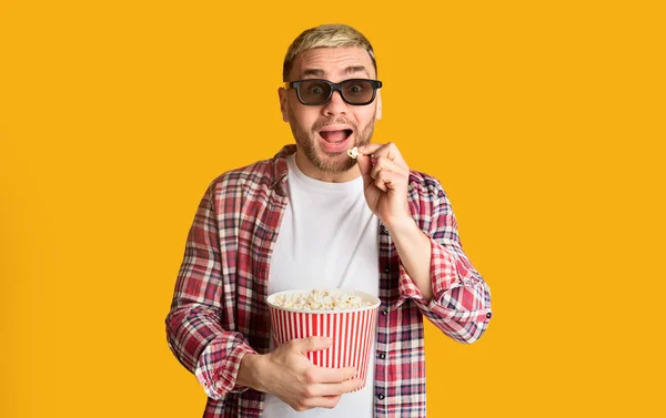 Un uomo al cinema divertente. Giovane maschio mangia popcorn — Foto Stock