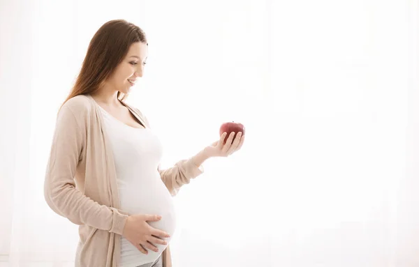 Mujer embarazada comiendo manzana en la cama en casa — Foto de Stock