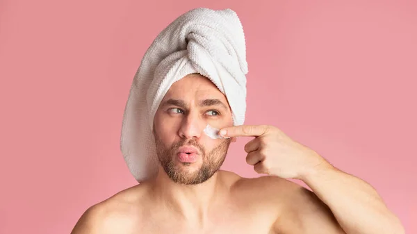 Guy with towel on his head smears his face with cream — Stock Photo, Image