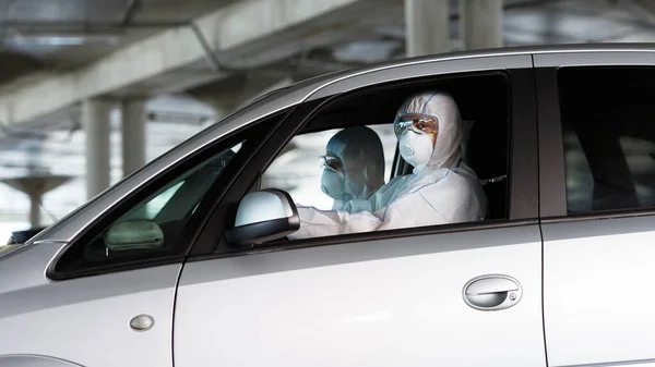 Zdravotničtí pracovníci v koronavirových oblecích řídí auto a hledají nemocné lidi — Stock fotografie