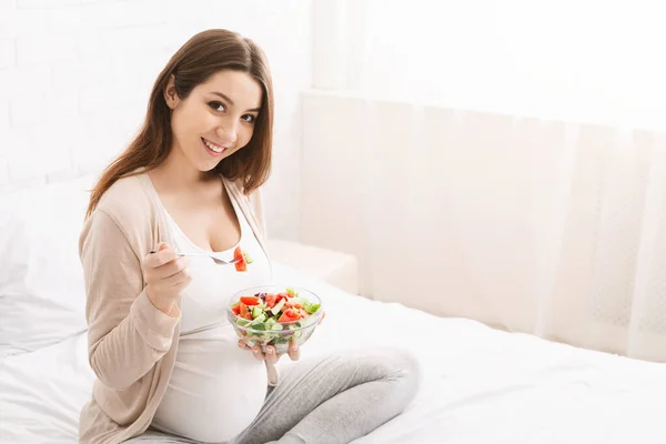 Wanita hamil menikmati sayuran segar salad di tempat tidur — Stok Foto