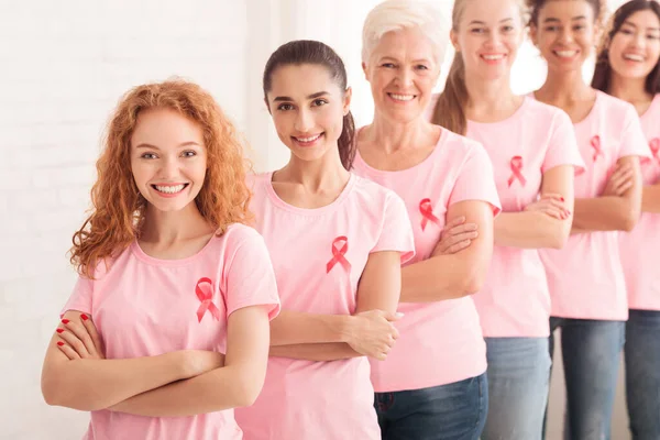 Voluntarios en camisetas de conciencia rosa de pie juntos sobre fondo blanco — Foto de Stock