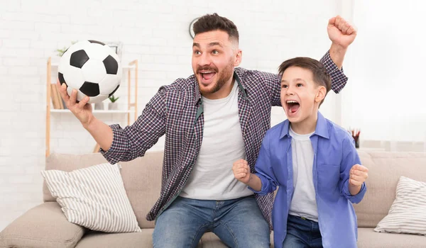 Emocional pai e filho com bola de futebol assistindo esporte na tve — Fotografia de Stock