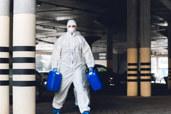 Werknemer in beschermend pak maakt natte desinfectie van straten — Stockfoto
