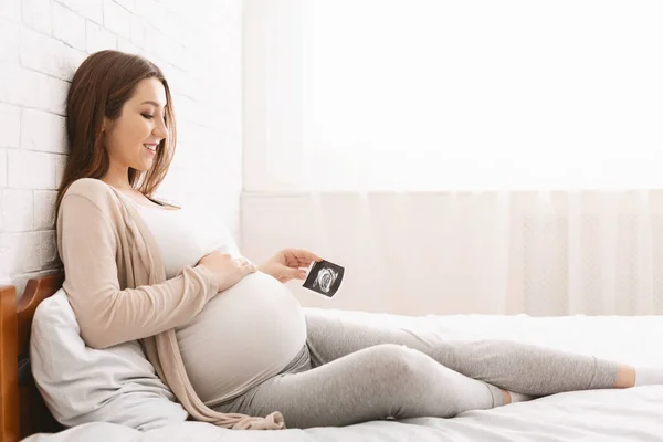 Femme enceinte jouissant de la maternité future avec la première photo échographie — Photo