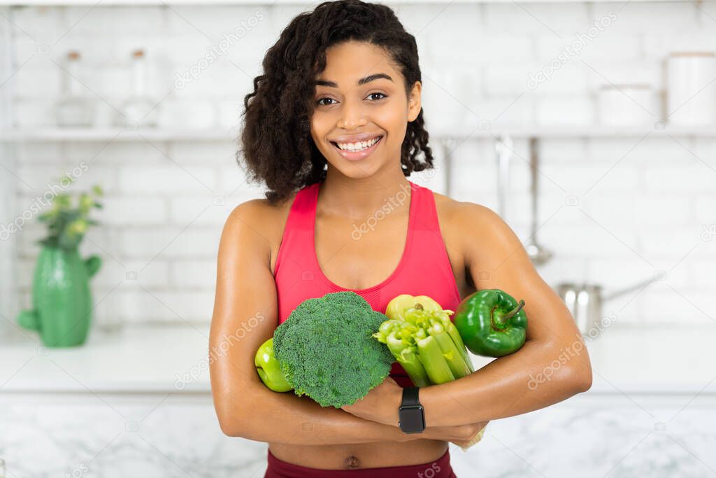 Happy young african girl holding green vegetables