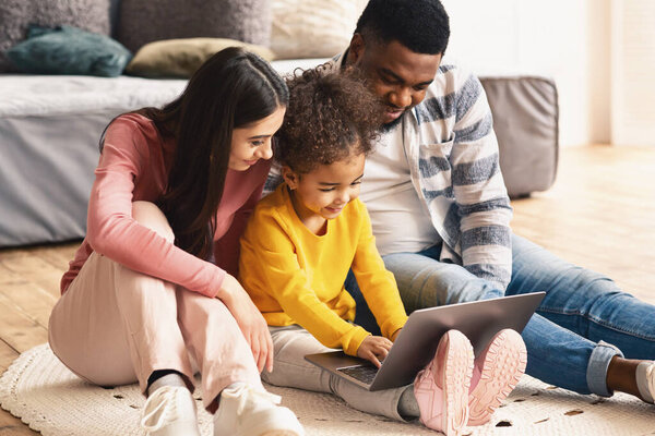 Girl is typing at laptop, parents help her