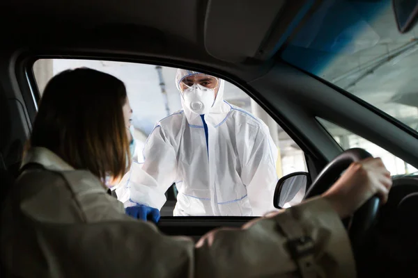 Mulher com máscara protetora sentada no carro e conversando com o médico assistente — Fotografia de Stock