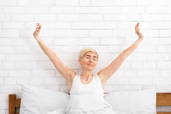 Bela mulher de meia-idade acordando em sua cama — Fotografia de Stock