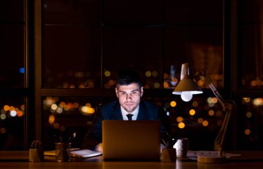 Laptop 'taki kendine güvenen girişimci geceleri ofiste oturuyor.