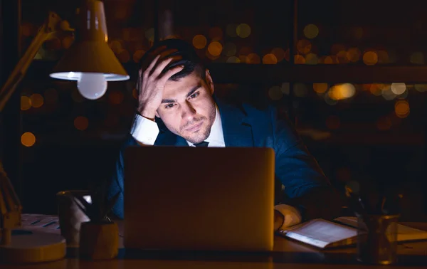 Entrepreneur à l'ordinateur portable pensant toucher la tête assis toute la nuit au bureau — Photo