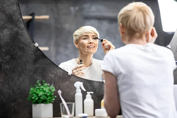 Volwassen dame van toepassing mascara op wimpers in badkamer thuis — Stockfoto