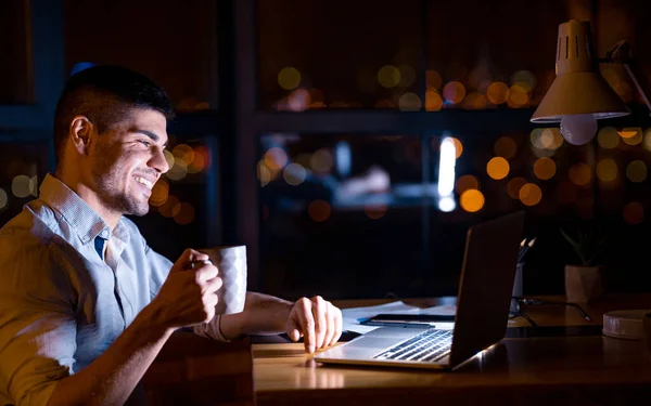 Buon imprenditore seduto al computer portatile che prende il caffè sul posto di lavoro — Foto Stock