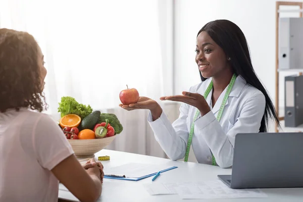 Positive african nutritionist recommending fresh fruits to eat — Stock Photo, Image