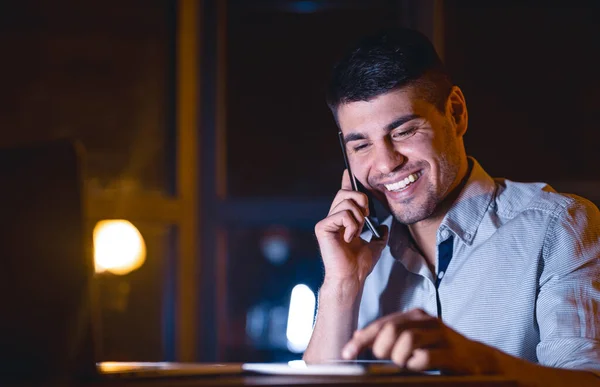 Uomo d'affari avendo piacevole conversazione telefonica seduto in ufficio di notte — Foto Stock