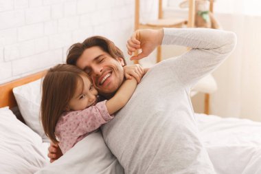 Sevimli kız uyandıktan sonra mutlu babasına sarılıyor.
