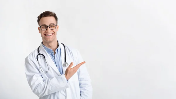 Médico sorridente no casaco aponta para lugar livre — Fotografia de Stock
