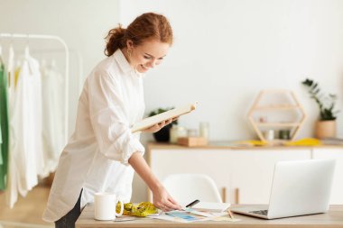 Kadın moda tasarımcısı elinde renk örnekleri tutuyor.
