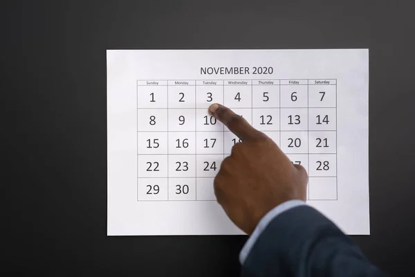 Αφρικανός άνδρας δείχνει με το δάχτυλο σε ημερολογιακή ημερομηνία — Φωτογραφία Αρχείου