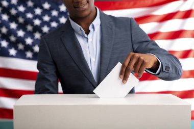 Mutlu Afrikalı Amerikalı adam oy sandığına kağıt sokuyor.