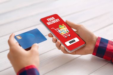 Yemek dağıtım uygulaması olan kredi kartı ve akıllı telefon tutan erkek eller.