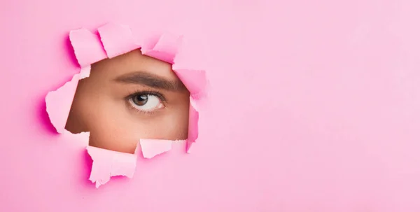 Mulher com maquiagem natural olhando através de papel rasgado — Fotografia de Stock