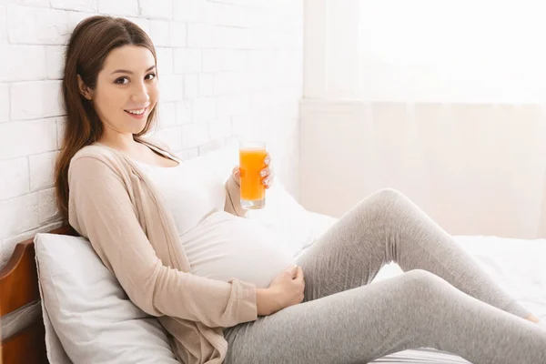 Hamile kadın taze yapılmış portakal suyuyla bardaktan zevk alıyor. — Stok fotoğraf