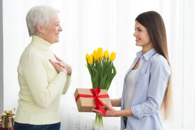 Kadın, olgun annesine lale ve hediye kutusu veriyor.
