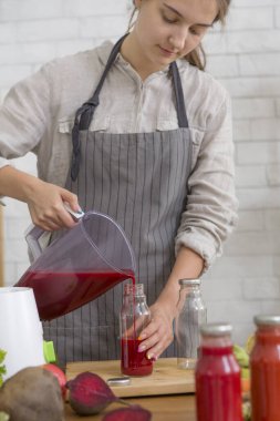 Genç bayan taze sebzelerle smoothie yapıyor.