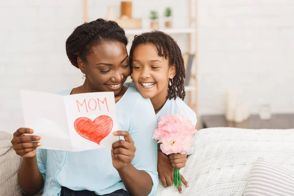 Το μαύρο κορίτσι χαιρετά τη μαμά της με λουλούδια και κάρτα. — Φωτογραφία Αρχείου